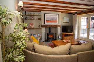 Living room with wood burner, TV and French doors leading to the patio