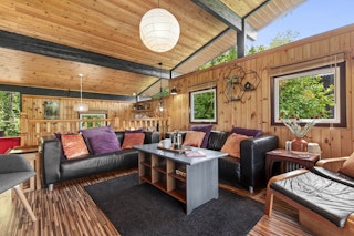 The living are has two sofas, a coffee table, wood interior and large windows