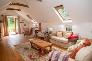 Living room with vaulted ceiling and exposed beams: sofas , armchairs and coffee table