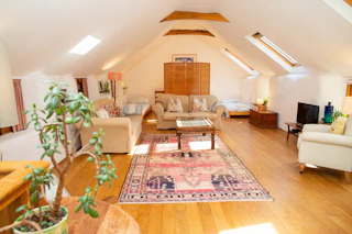 Living room with vaulted ceiling and exposed beams: sofas, armchair and coffee table