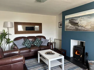 Living room with leather sofa and armchair, coffee table, standard lamp and log burner