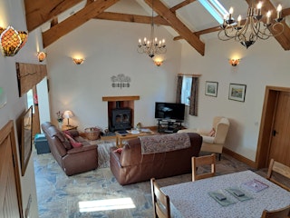Living and dining area with table and chairs, sofas, armchairs and log burner