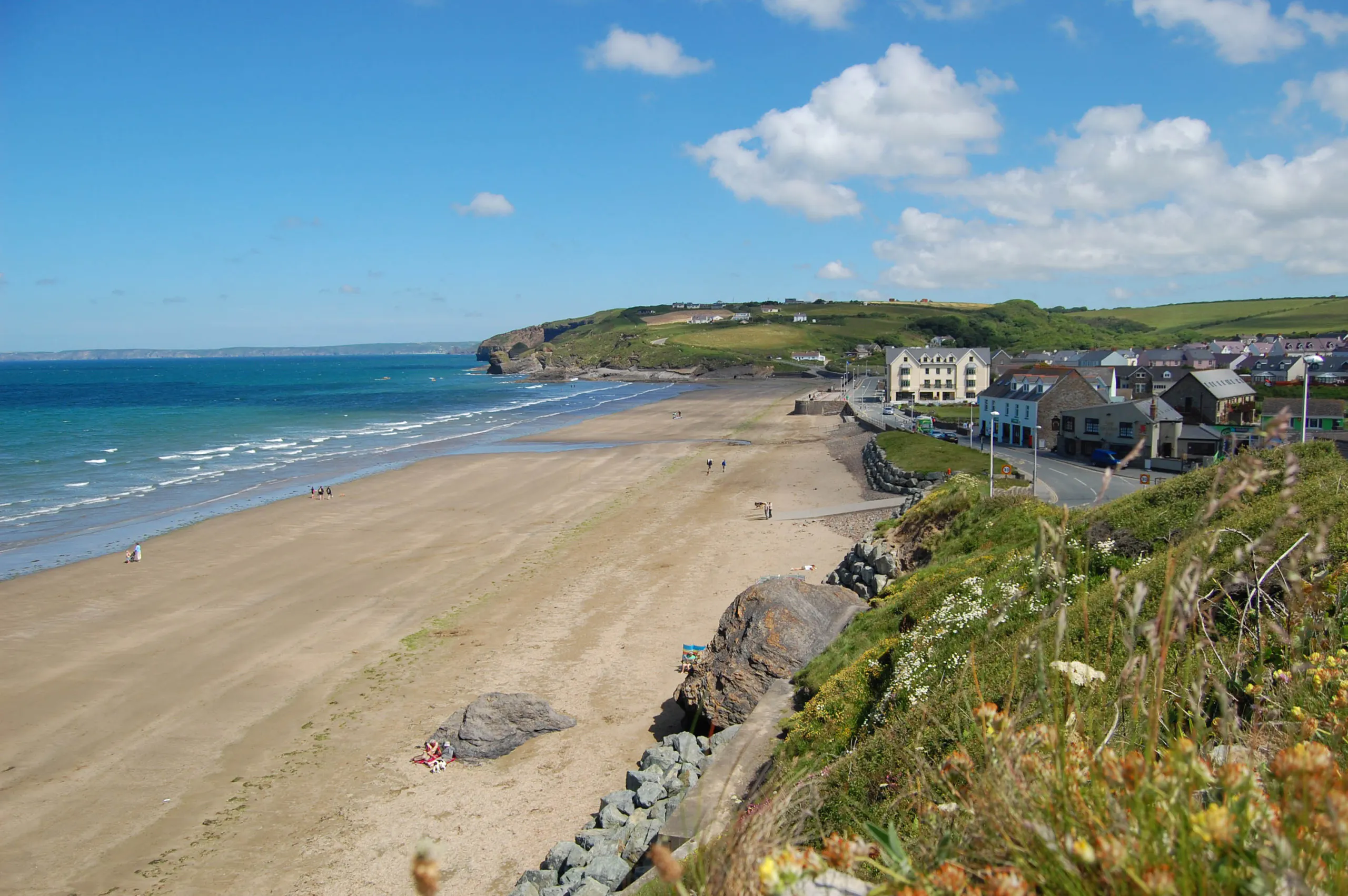 Long sandy shoreline with sea, distant headland, and buildings near the beach