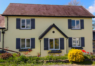 Front of cottage, porch, window boxes with flowers, front garden and gravel area