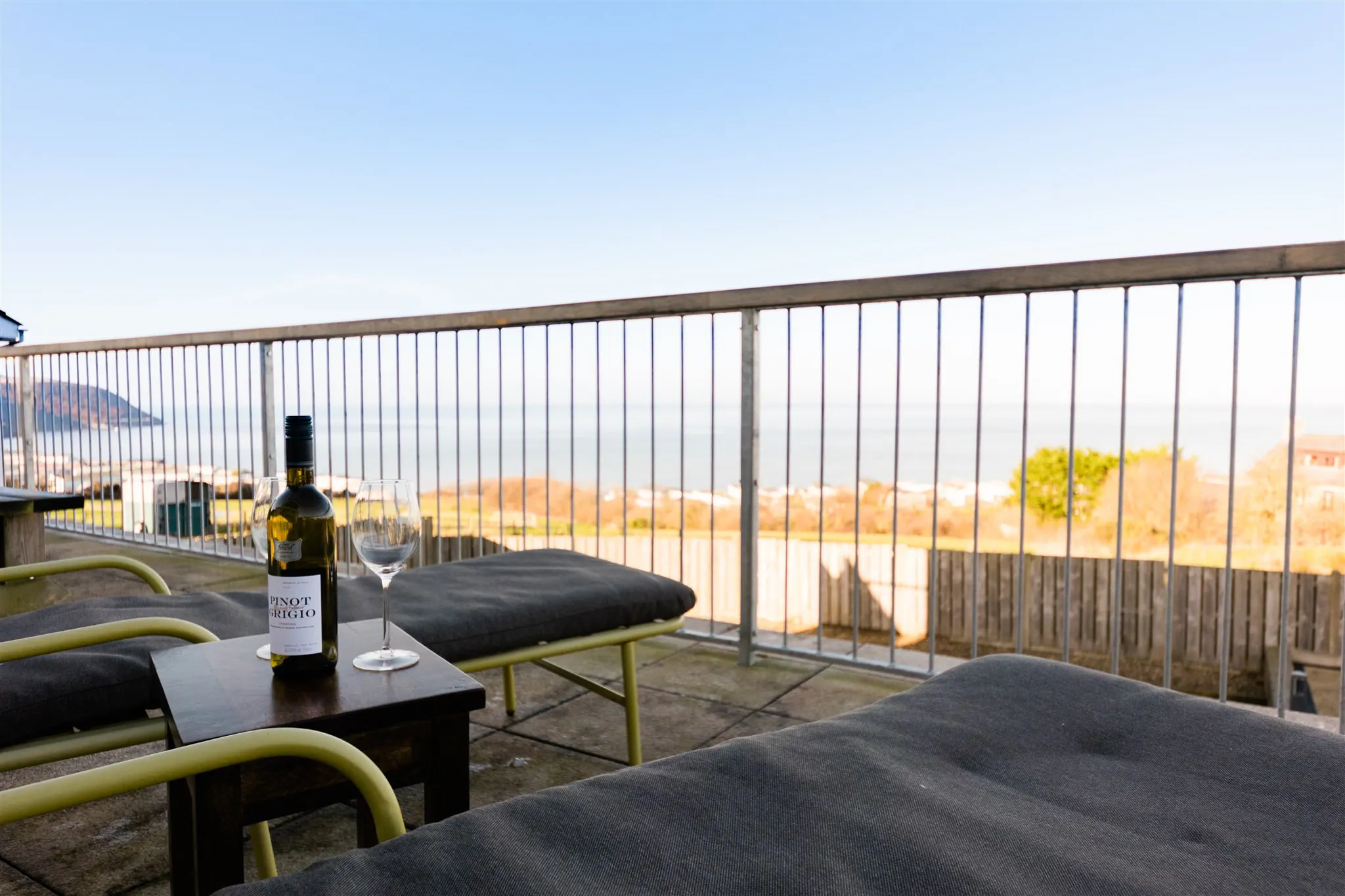 Bottle of wine and two glasses on a terrace with sun loungers and sea view