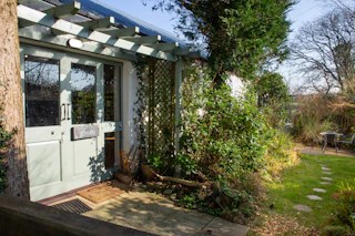 Front entrance with pale green double doors under a pergola