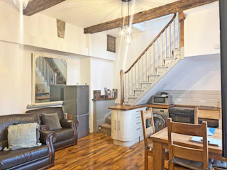 Open-plan room with leather sofa, dining table and staircase to mezzanine