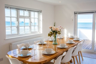 Dining table laid for dinner. Patio doors leading to the balcony