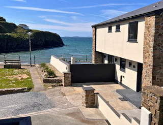 Seafront house exterior with terrace walls and path leading towards the water