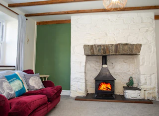 Living room with sofa and cushions, fireplace with log burner, beamed ceiling