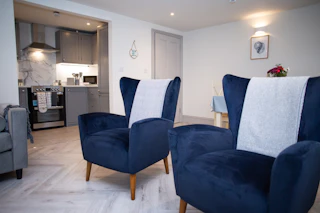 Two large armchairs in the living area with a view into the kitchen