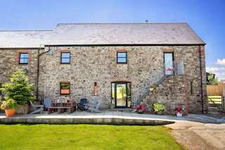 Stone cottage with patio seating and lawn in front