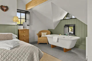 Bedroom with freestanding bath under sloped ceiling and skylight