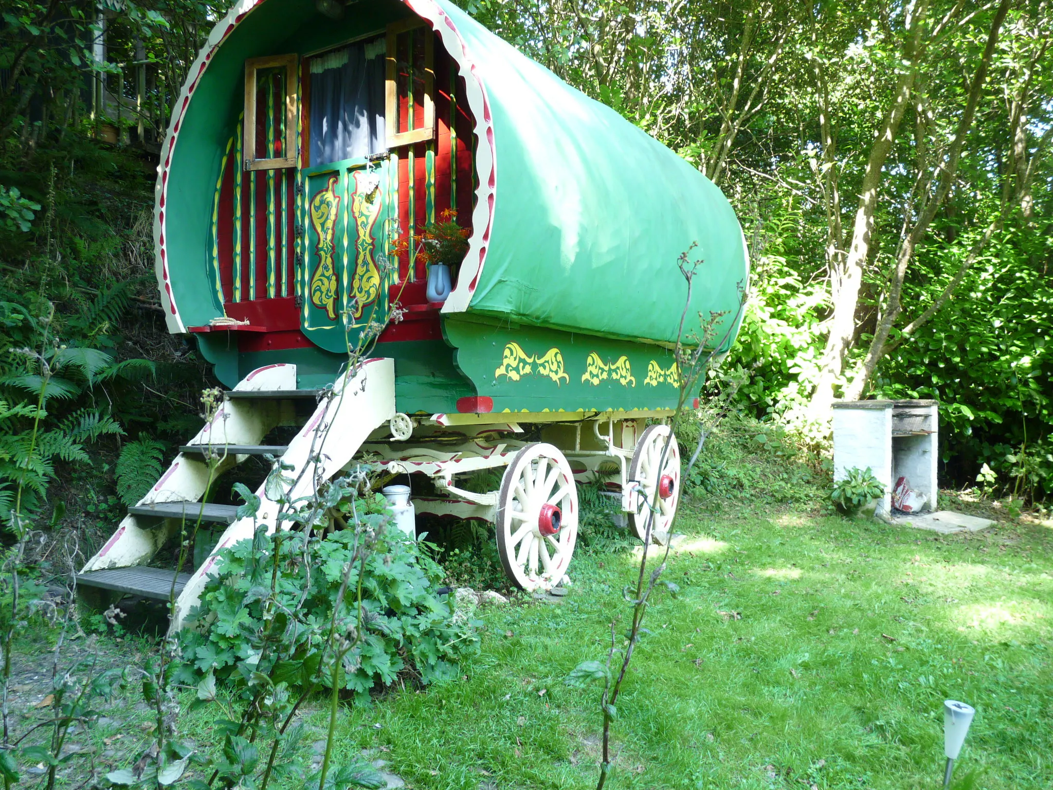 Romany Wagon Retreat surrounded by lawns and trees, barbecue