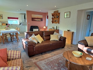 2 seater sofa with cushions, coffee table, view into dining area and kitchen