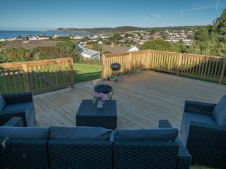 Caerllan deck with table and chairs, barbecue and views across Aberporth to the sea