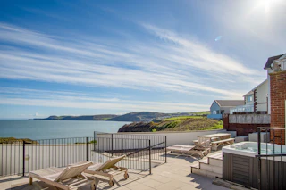 Clifftop Haven patio with seating areas, hot tub and sea and coastline views