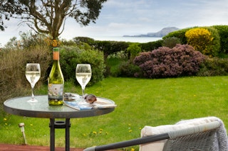 Garden with small picnic table and chairs, lawn and view towards the sea