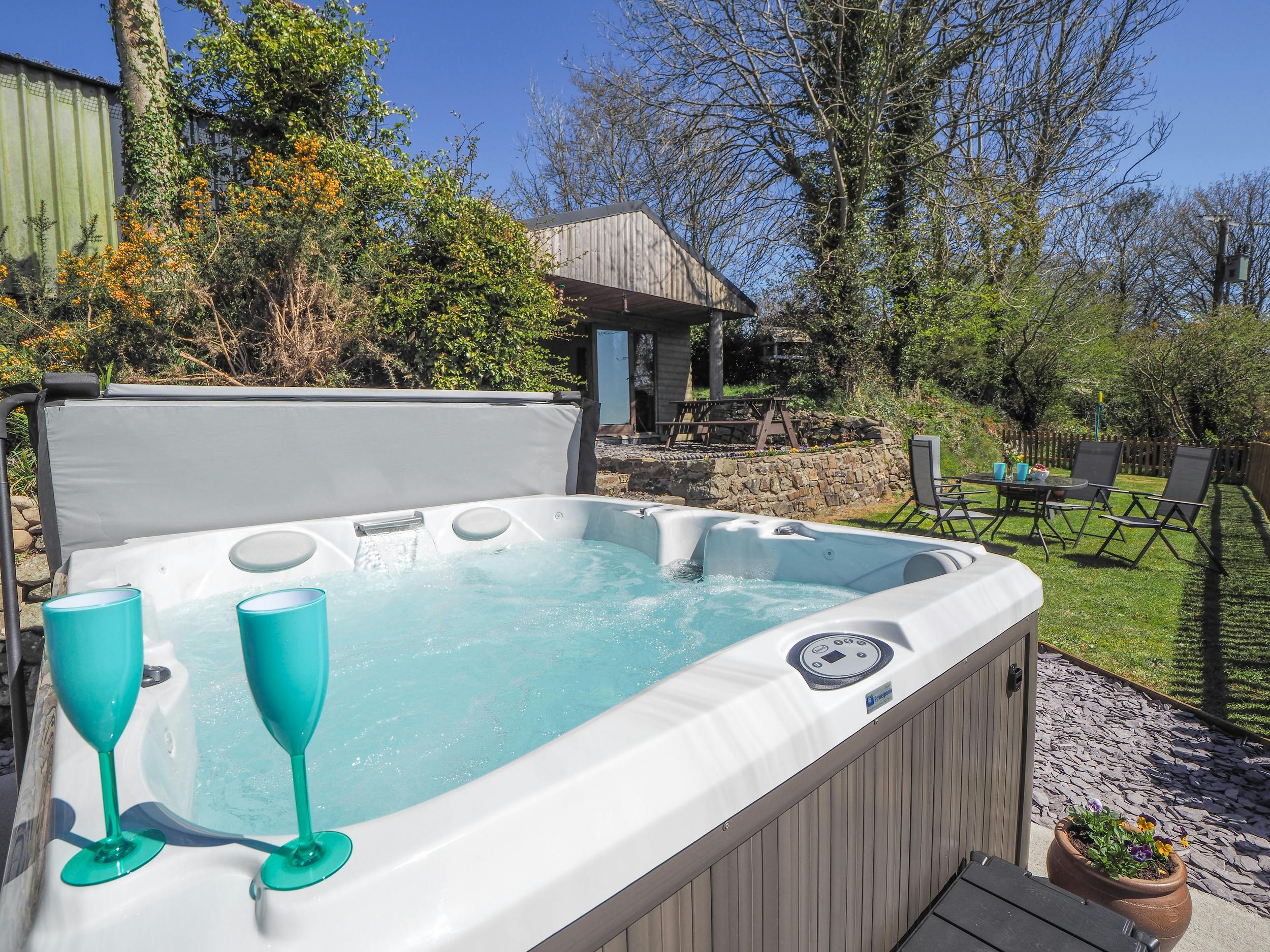 Caban Cynnes hot tub with two blue wine glasses and lawn in background