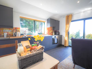 Kitchen area on one side with table and chairs, welcome pack and sofa on the other side