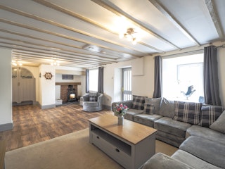 Lounge with large grey corner sofa. Large coffee table with vase of flowers