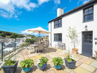 Front of the house has a bench and flower pots.